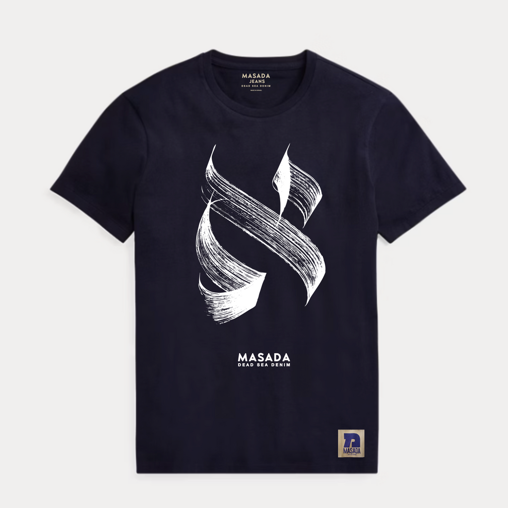 The Aleph white T-shirt, made from premium cotton, showcases a striking black abstract brushstroke inspired by Israeli culture, "MASADA DEAD SEA SWIM" text underneath, and a small Masada logo patch at the bottom right.