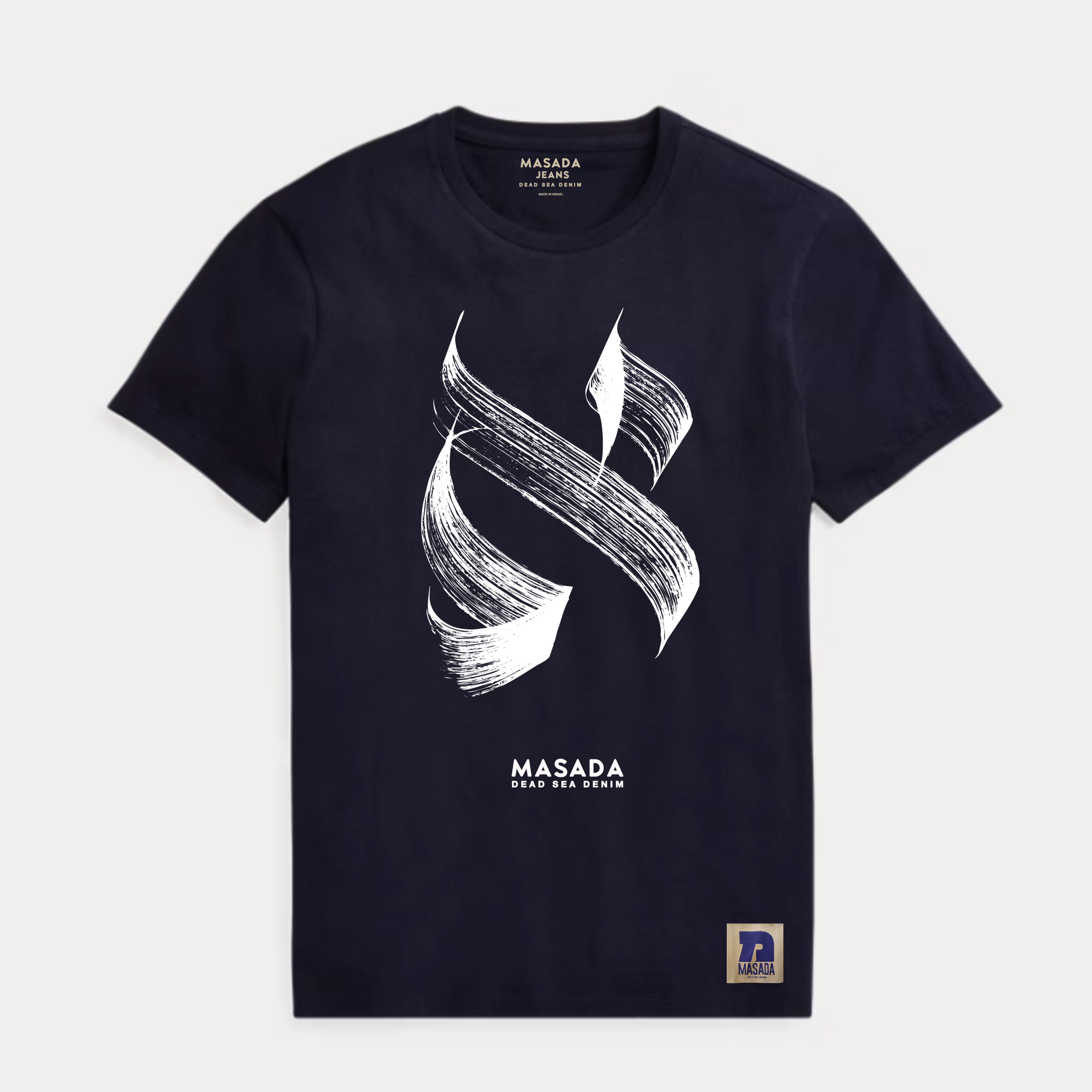 The Aleph white T-shirt, made from premium cotton, showcases a striking black abstract brushstroke inspired by Israeli culture, "MASADA DEAD SEA SWIM" text underneath, and a small Masada logo patch at the bottom right.