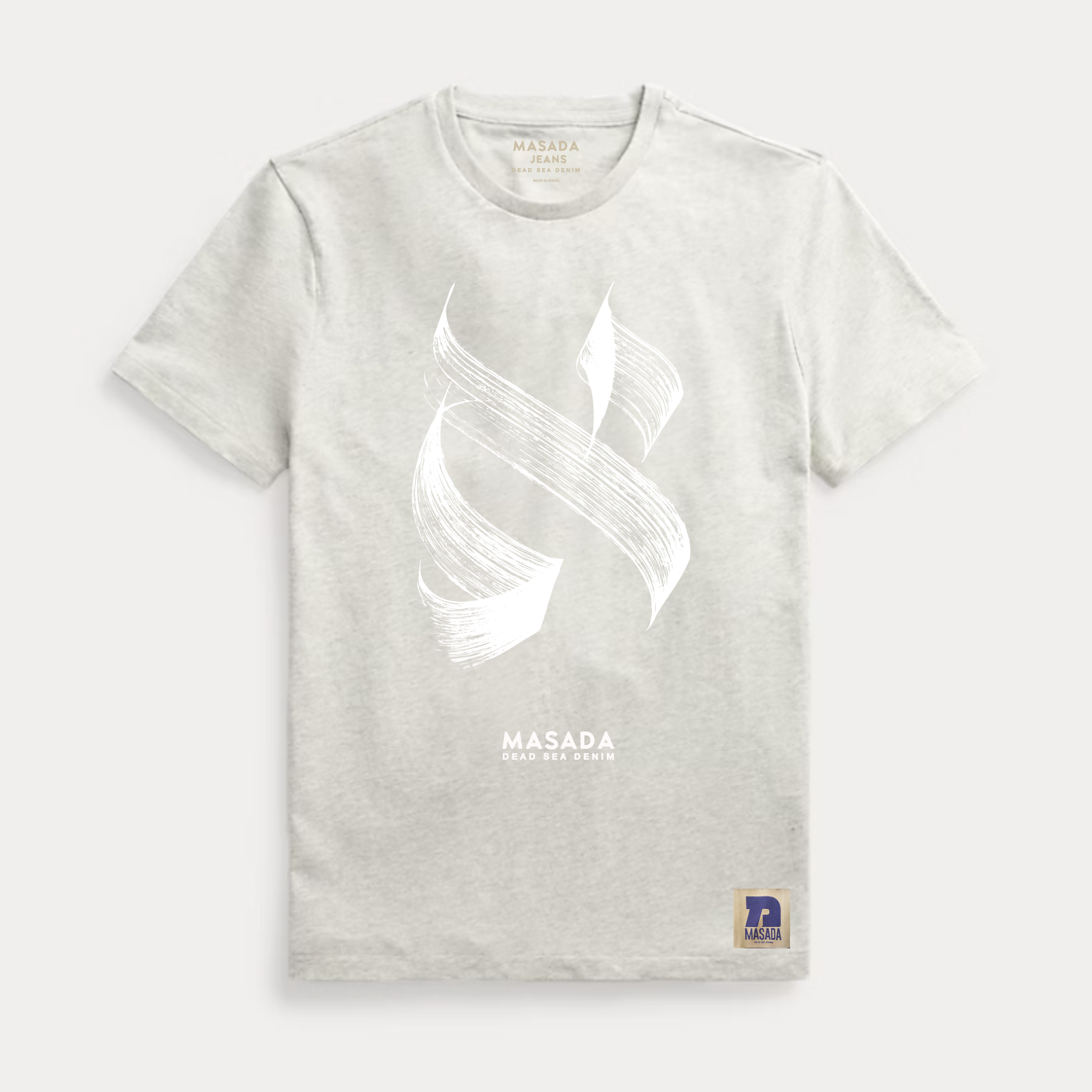 The Aleph white T-shirt features a premium cotton build with an abstract white brushstroke on the chest, MASADA DEAD SEA DEPTH text below, and a blue and gold patch at the hem—a nod to modern Israeli culture.